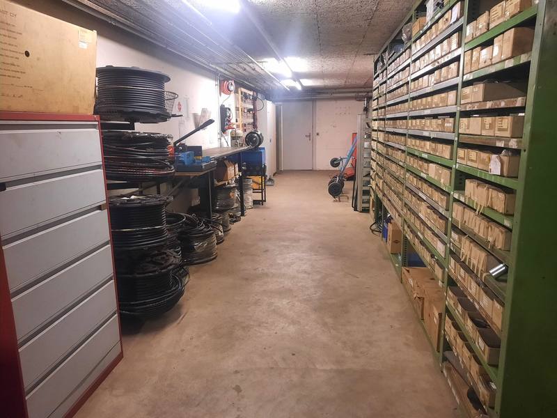 Ersatzteillager mit Regalen voller Schachteln und Rollen mit Hydraulikschlauch