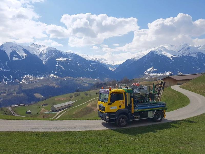 Separator-Lastwagen auf einer Bergstrasse vor schneebedeckten Bündner Bergen