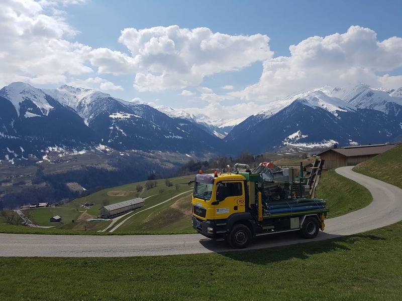 Separator-Lastwagen auf einer Bergstrasse vor schneebedeckten Bündner Bergen
