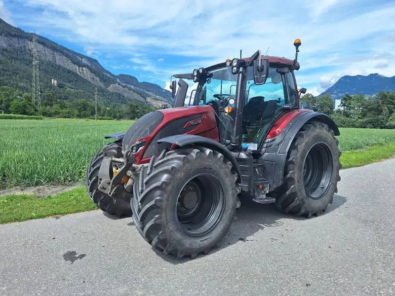 Valtra N175D, dunkelrot, auf einer Feldstrasse vor Wiese und Bergen