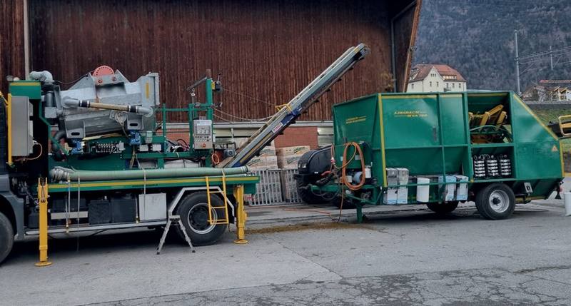 Gülle-Separator auf einem Lastwagen und ein grüner Anhänger vor einer Scheune